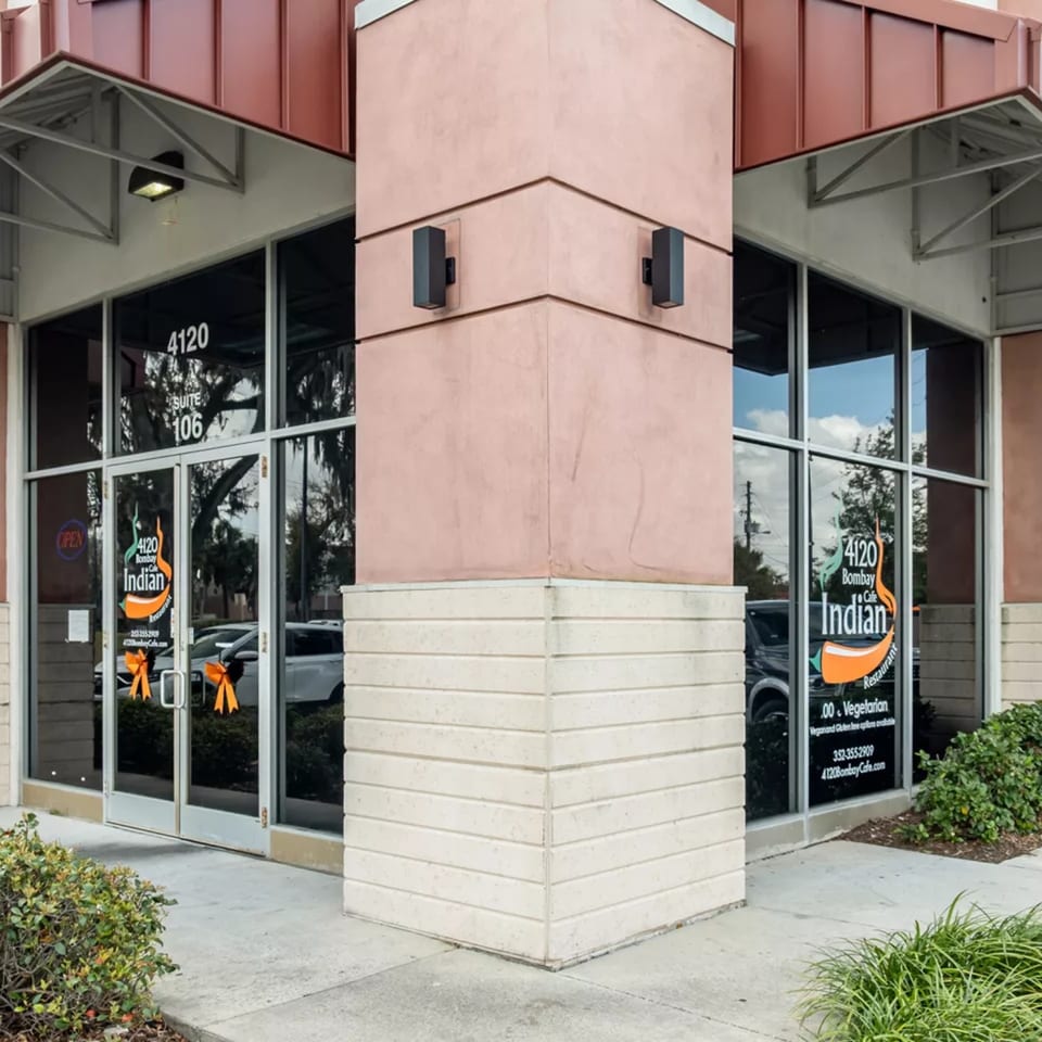 Exterior view of Bombay Cafe, an Indian restaurant, with large windows and signage.