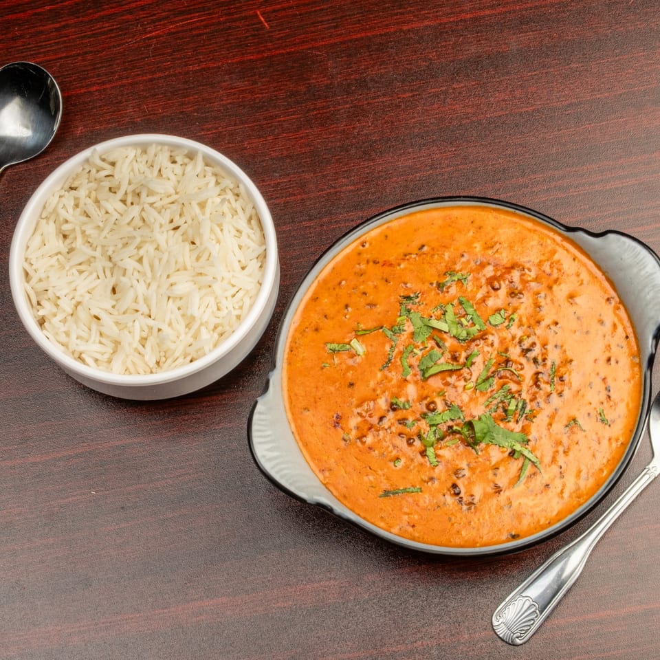 Bombay Cafe's creamy orange Indian curry with cilantro, served with a side of white rice.